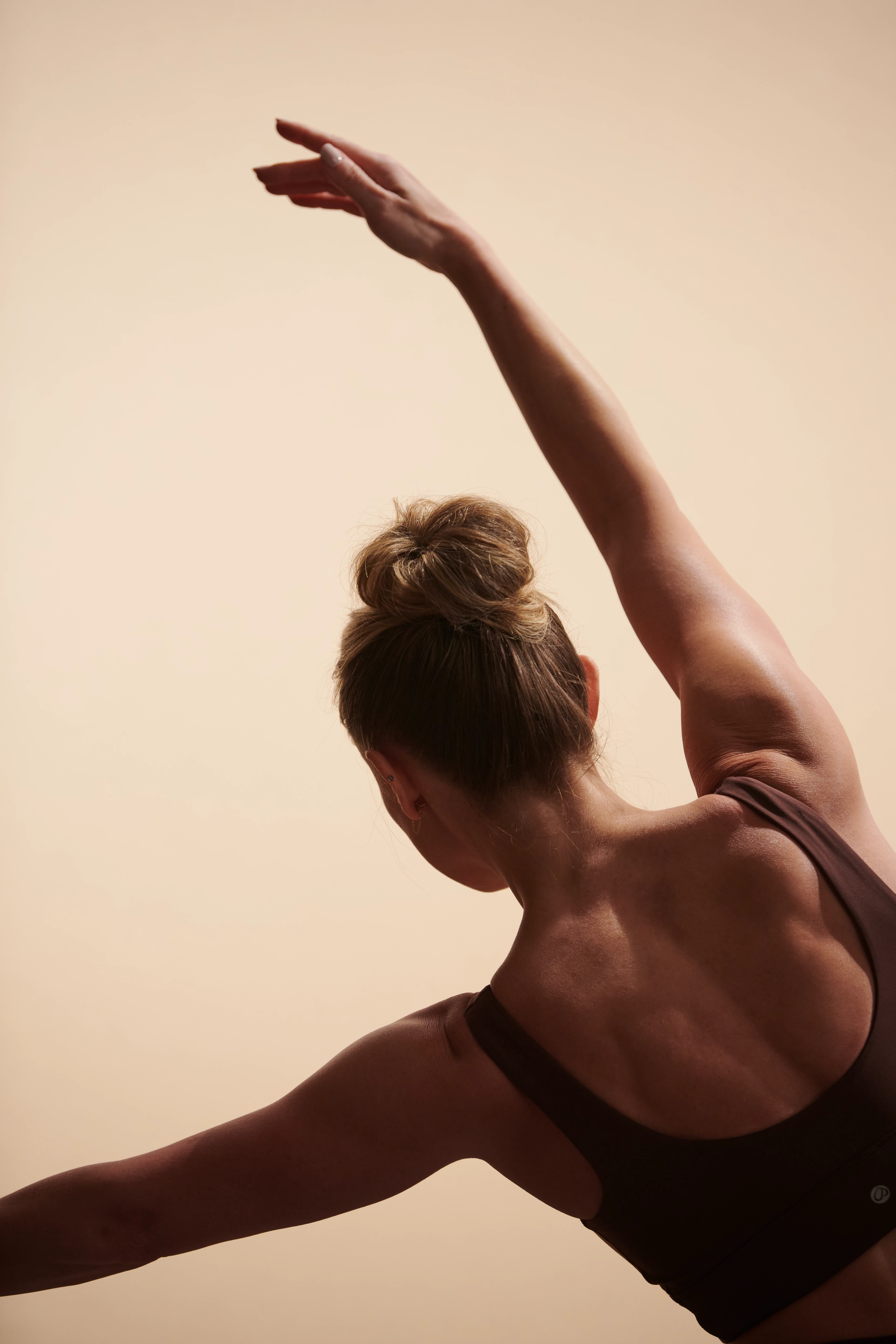 Closeup of a womans back while she stretches an arm above her head